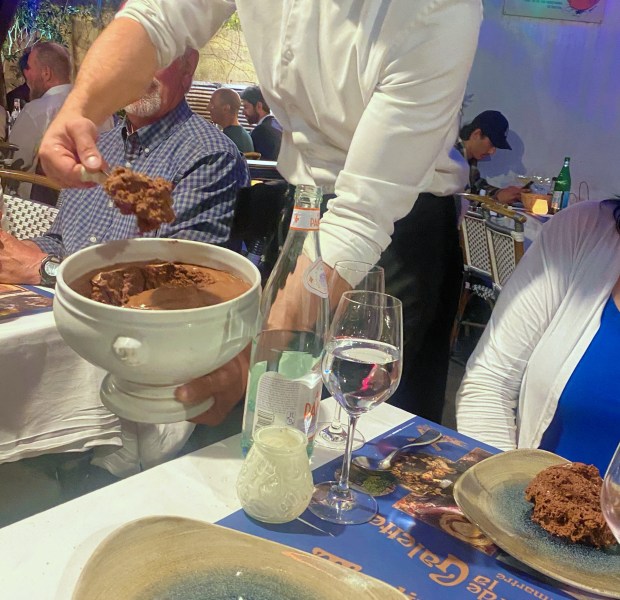 Chocolate souffle is ladled from a large bowl onto Sascha Nelson's plate at Le Moulin de la Galette, a 150-year-old restaurant in a one-time mill that was a favorite of the Impressionists and other artists. (Janet Podolak - For The News-Herald)