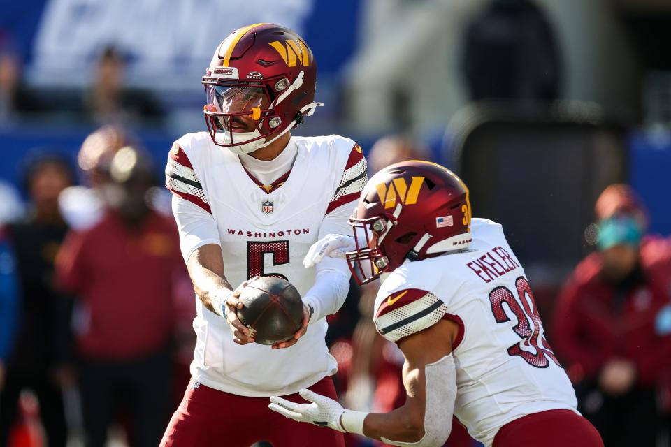 EAST RUTHERFORD, NEW JERSEY - NOVEMBER 03: Jayden Daniels #5 of the Washington Commanders hands the ball off to Austin Ekeler #30 during the first half against the New York Giants at MetLife Stadium on November 03, 2024 in East Rutherford, New Jersey. (Photo by Al Bello/Getty Images)