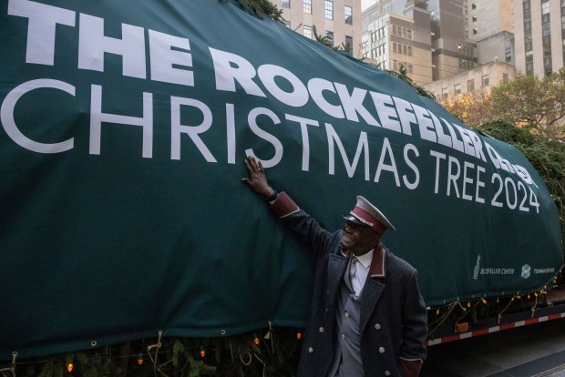 An employee touches the Rockefeller Center Christmas tree at Rockefeller Plaza, Saturday in New York. (AP Photo/Yuki Iwamura)