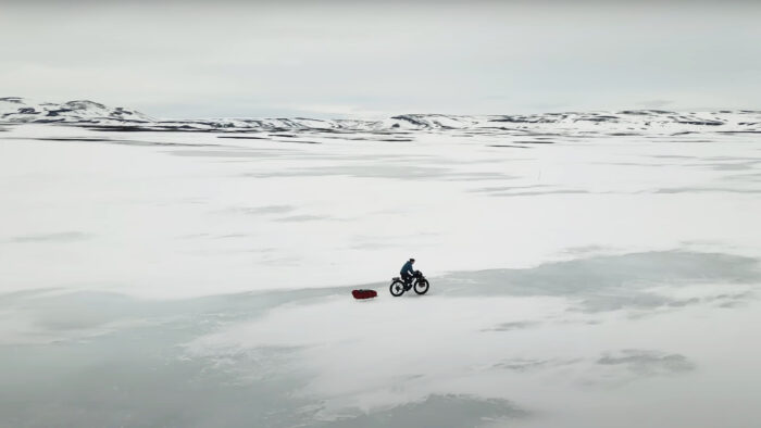 a man bikes and tows a sled across a winter landscape