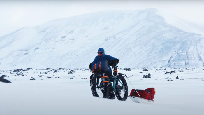 a man pushes a bike through a snowdrift