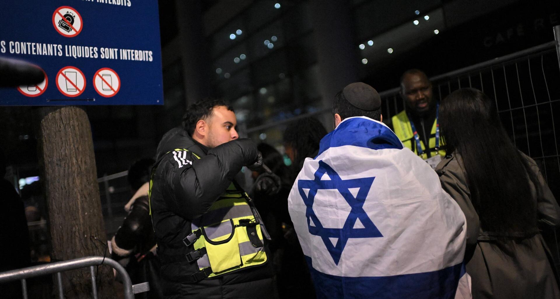 Israelische Fans kommen zum Spiel Frankreich gegen Israel und unterhalten sich mit der Polizei. Ein Fan hat eine Israel-Flagge um den Körper.