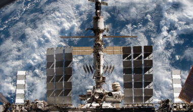 Space station leak: The space station with modules and solar panels all hooked together above a cloudy Earth.