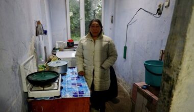 A woman in a winter jacket in a cramped kitchen