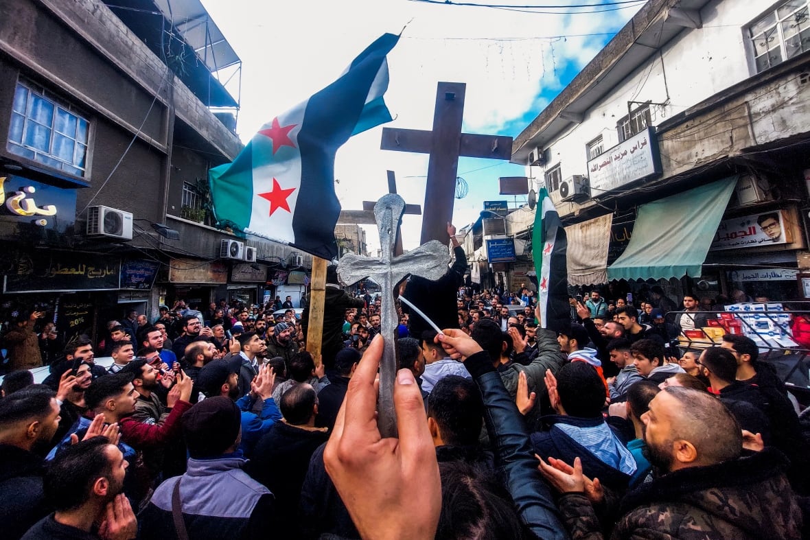 Christian Syrians lift crosses and independence-era flags at rally.