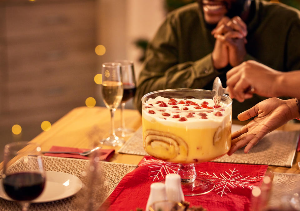 Christmas dessert at friends dinner for celebration or festive holiday at home. Party, food and group of people with trifle cake on dining room table