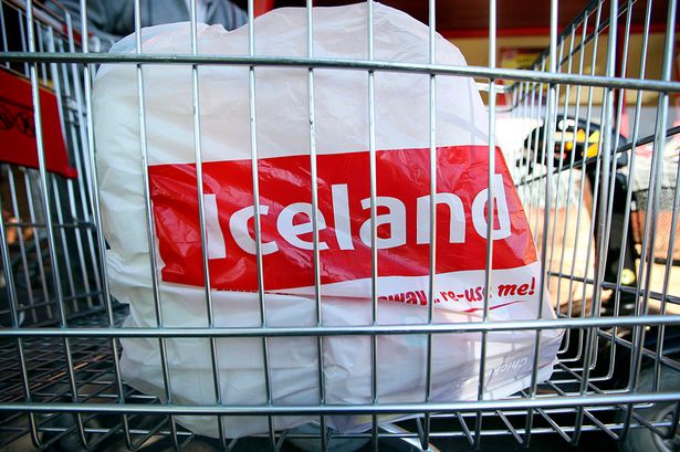 An Iceland  carrier bag sits in a shopping cart at a supermarket 