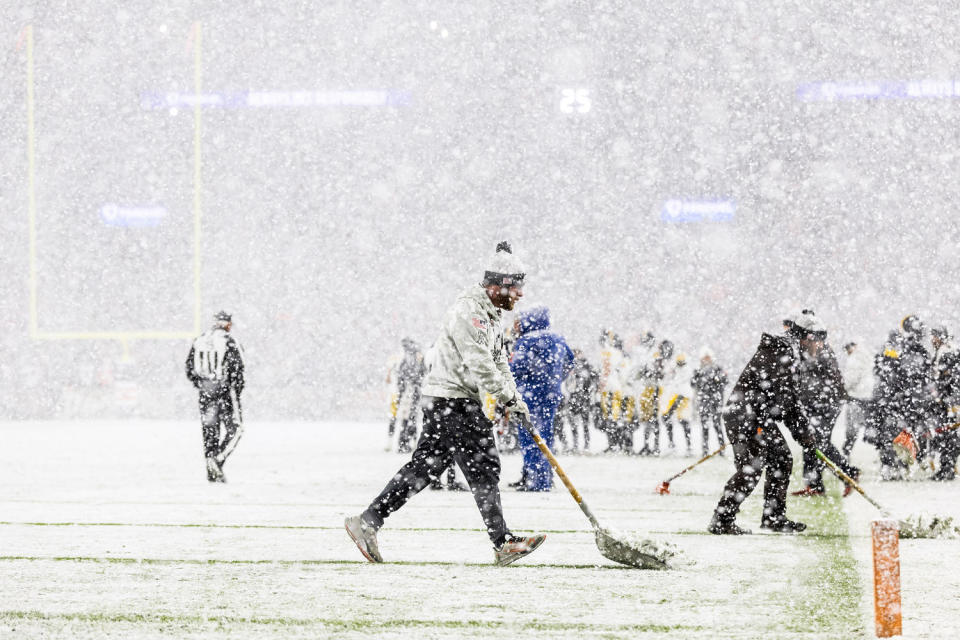 Grounds crew members shovels snow off the yard lines on a football field (Scott Galvin / Imagn Images)