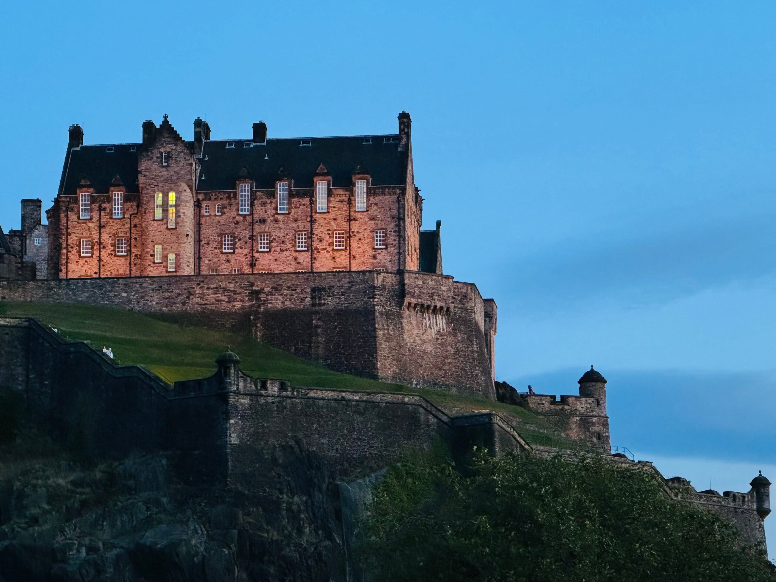 Edinburgh Castle, located near the side of a cliff, at dusk.