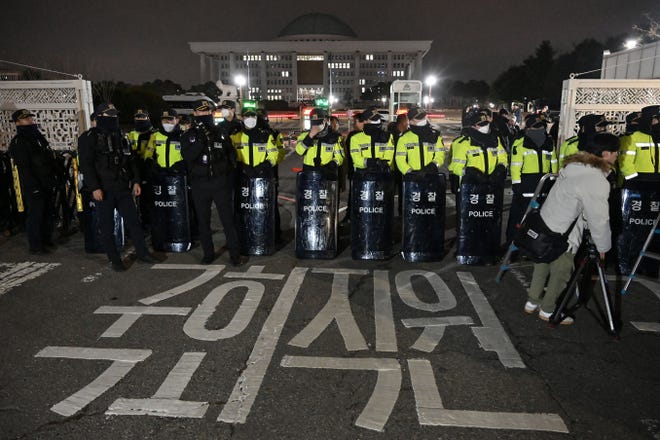 Police stand guard in front of the main gate of the National Assembly in Seoul, South Korea on December 3, 2024, after President Yoon Suk Yeol declared emergency martial law.