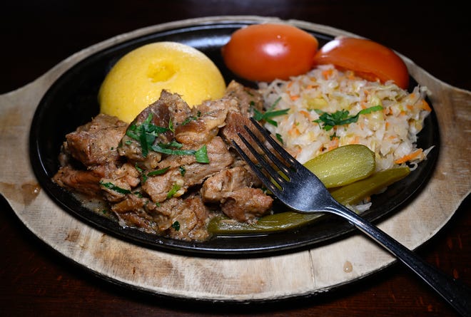 This dish featuring roasted pork stewed in broth, with onions and garlic and served with pickled vegetables and polenta, is among the most popular at Moldova in Newton, Dec. 19, 2024.