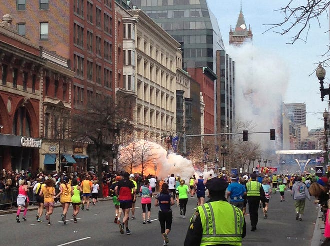 Runners continue to run towards the finish line of the Boston Marathon as an explosion erupts near the finish line of the race in this photo exclusively licensed to Reuters by photographer Dan Lampariello after he took the photo in Boston, Massachusetts, April 15, 2013.