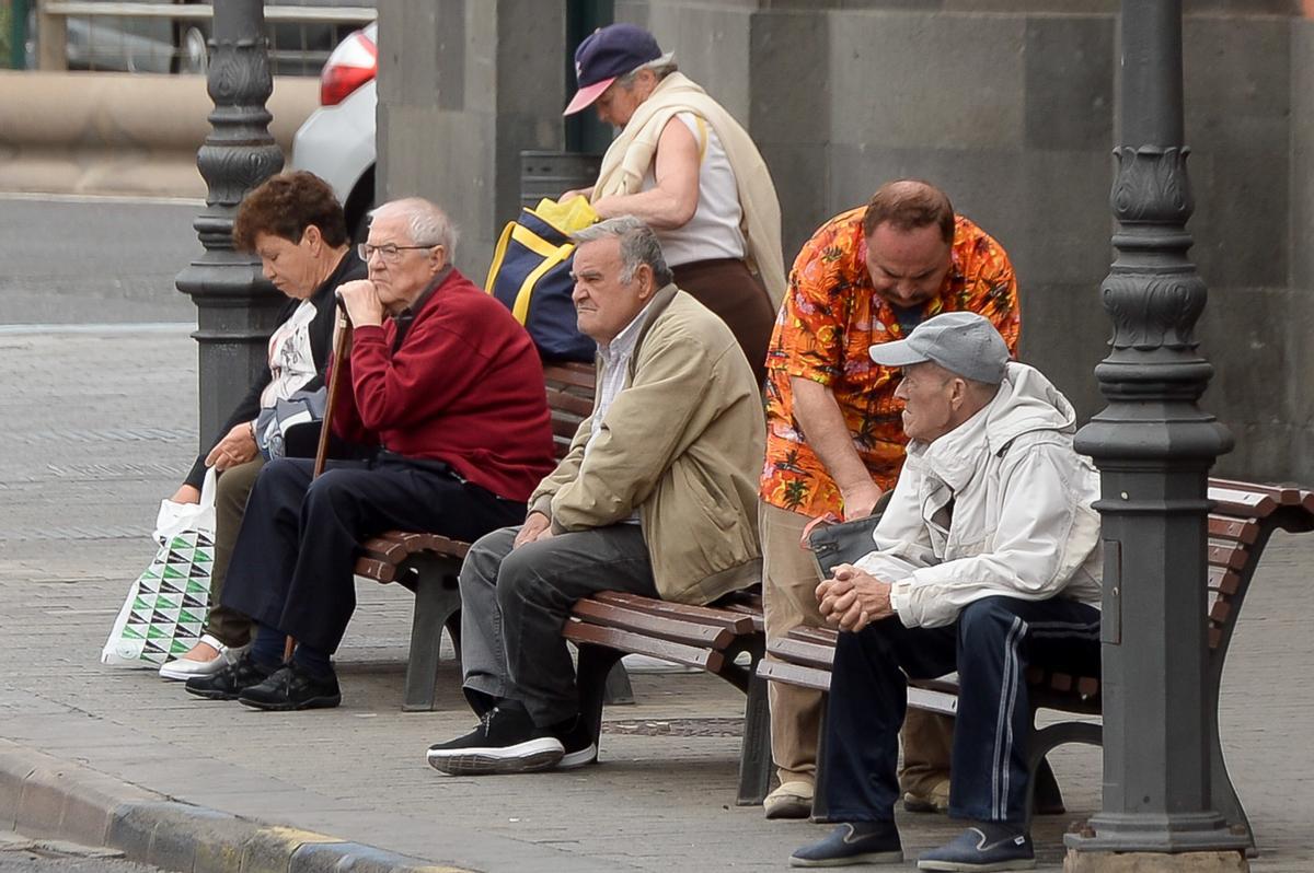 Varios jubilados descansan en un banco.