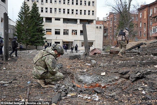 Ukrainian troops survey the site of a Russian missile strike on the city's Kyivskyi, November 25