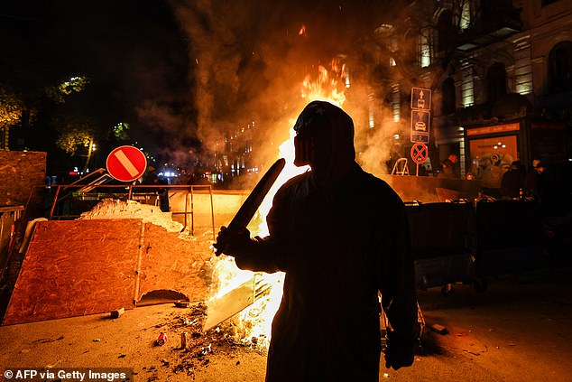 Protesters light a fire at the base of a makeshift barricade erected in a street in Tbilisi during demonstrations against the government's decision to delay European Union membership talks