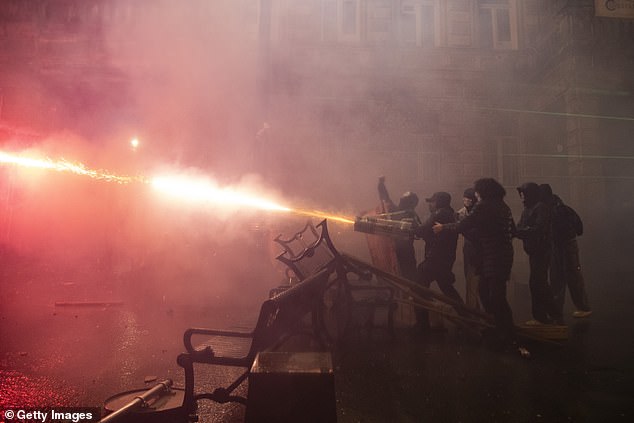 Demonstrators shoot fireworks at the police during a protest outside the parliament on November 30, 2024 in Tbilisi, Georgia