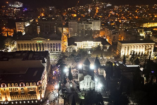 Demonstrators rally outside the parliament's building, center left, to protest the governments' decision to suspend negotiations on joining the European Union for four years in Tbilisi, Georgia, on Saturday, Nov. 30, 2024