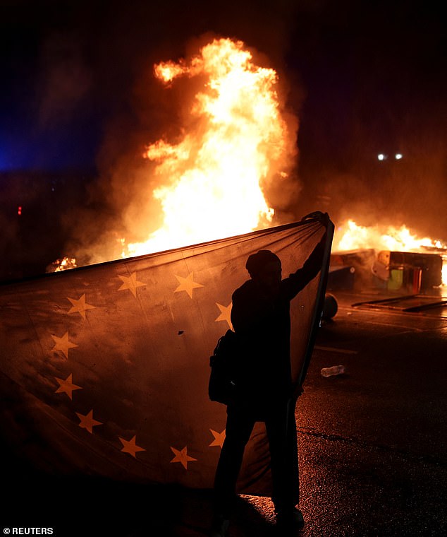 A supporter of Georgia's opposition holds a European Union flag while attending a rally to protest after the government halted the EU application process until 2028