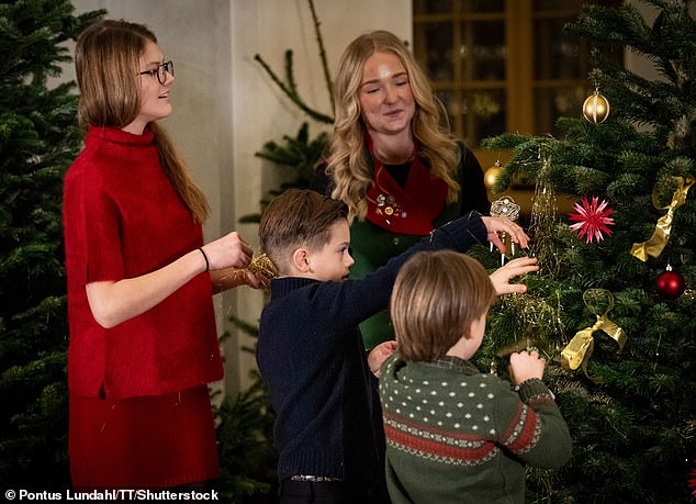 Princess Estelle, Prince Oscar, and Prince Gabriel hang up their Christmas decorations on one of the trees at the Royal Palace