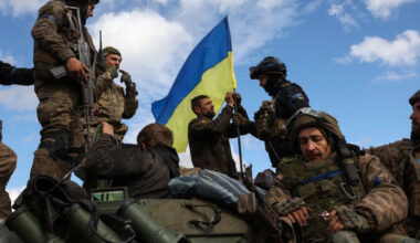 Ukrainian soldiers adjust a national flag atop a personnel armored carrier on a road near Lyman in the Donetsk region on Oct. 4, amid the Russian invasion of Ukraine