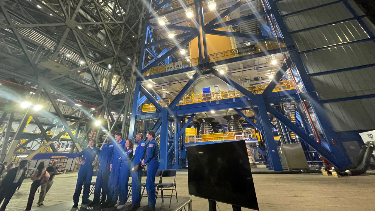 Artemis II crew pose in front of the SLS core stage inside the Kennedy Space Center Vehicle Assembly Building. (Spectrum News)