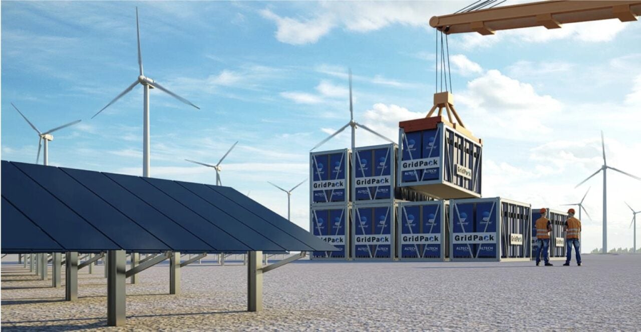 Computer-generated composite image shows Altech battery storage containers lowered by crane onto a renewable energy project site as two workers in high-vis clothing look on.
