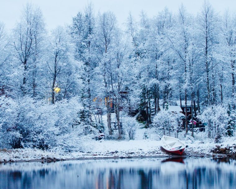 Snow covering winter morning on Lake Inari with boat on foreground.