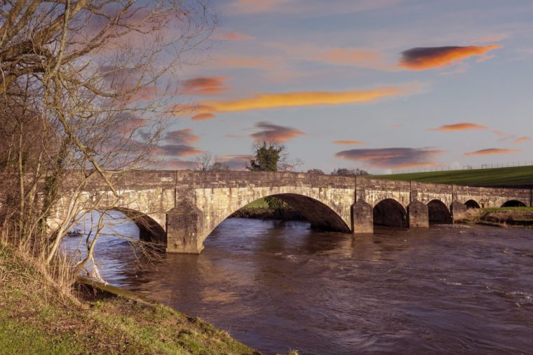 Dramatic clouds at sunset over bridge crossing River Ribble near Clitheroe in Lancashire, England.