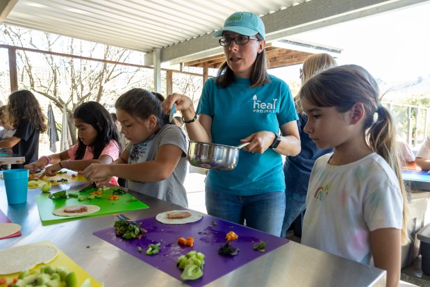 Sara Neale, farm educator at the HEAL Project, helps El Granada Elementary School 3rd graders prepare veggie tacos after harvesting produce on a farm field trip Wednesday, Oct. 23, 2024, in Half Moon Bay, Calif. (Karl Mondon/Bay Area News Group)