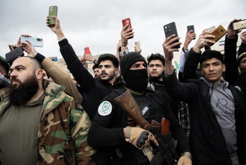 People take photos as Syrian opposition fighters hold a military parade in Damascus, Syria, on Friday. Members of Hay'at Tahrir al-Sham, or HTS, marched to send a message of strength and reassurance to the people, according to HTS. Photo by Hasan Belal/EPA-EFE