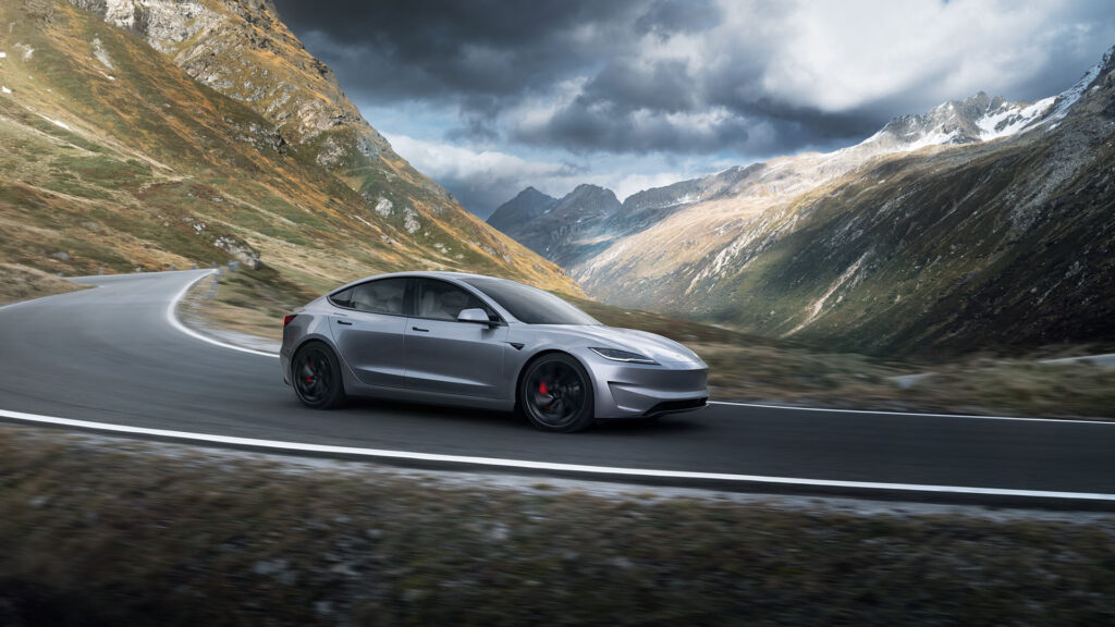 Tesla Model 3 in Quicksilver color driving down a mountainous highway.