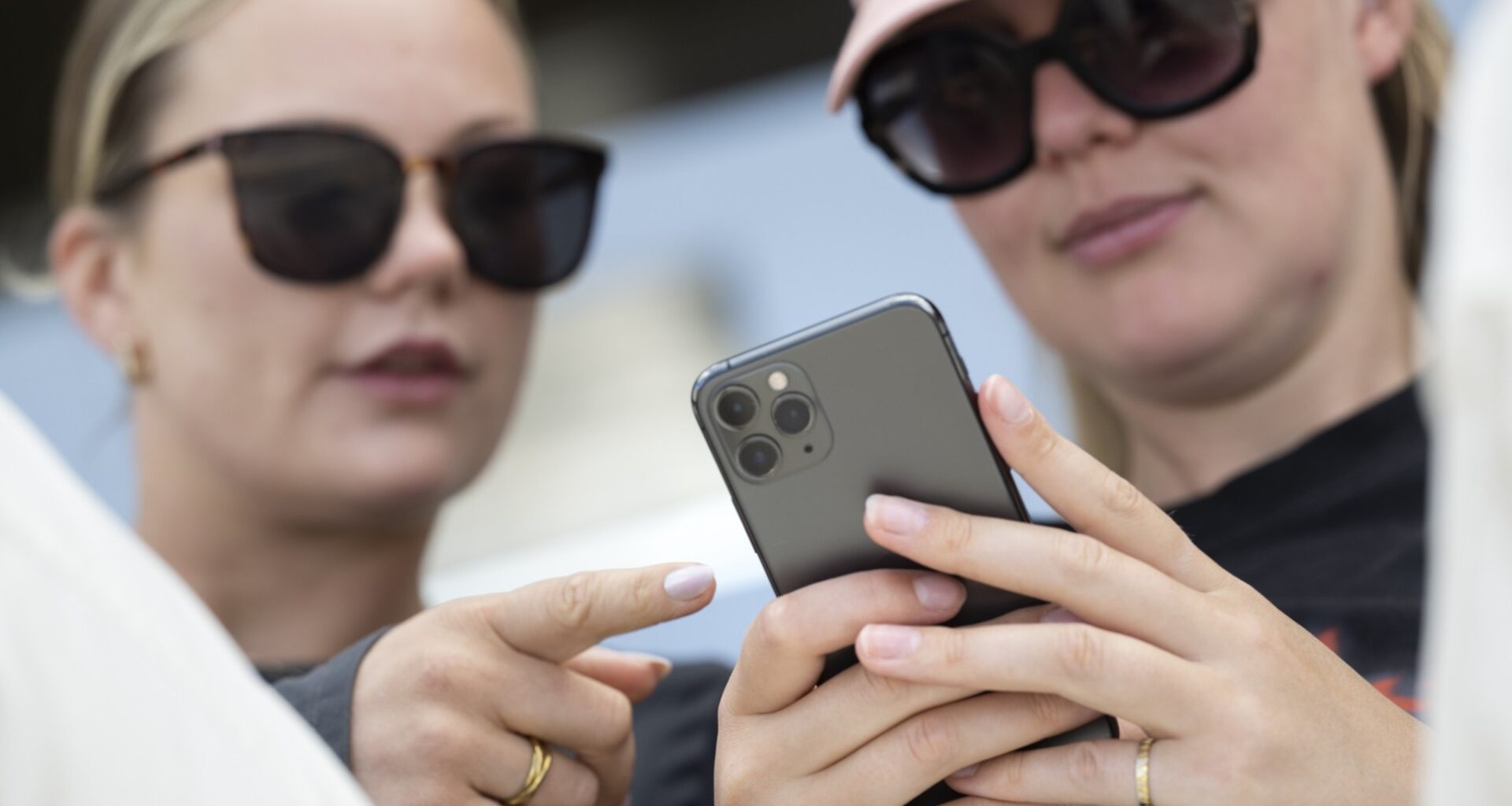 två unga kvinnor tittar på en mobiltelefon