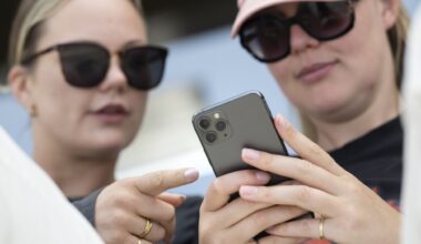 två unga kvinnor tittar på en mobiltelefon