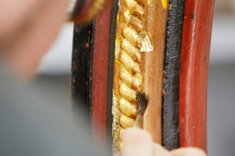 Conservator Matthias Manzini uses a gilding brush made from squirrel hair to apply the delicate gold leaf to the carriage wheel he is restoring (Alex HALADA)