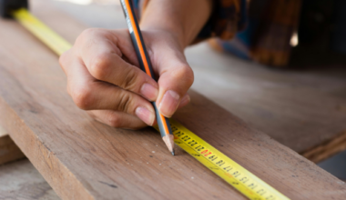 A person marking a spot next to a measuring tape