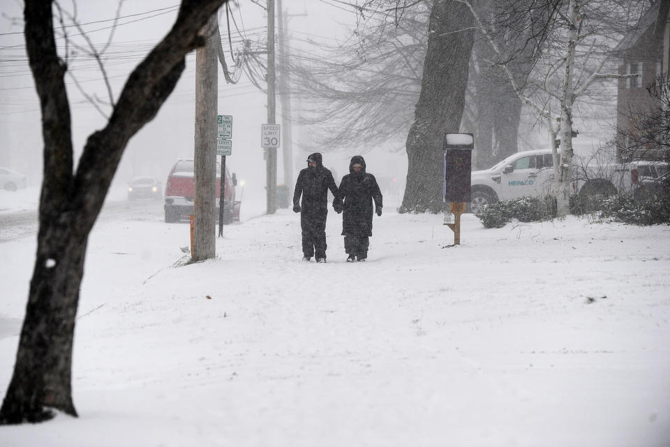 A couple makes their way through snow on a sidewalk (John Normile / Getty Images)