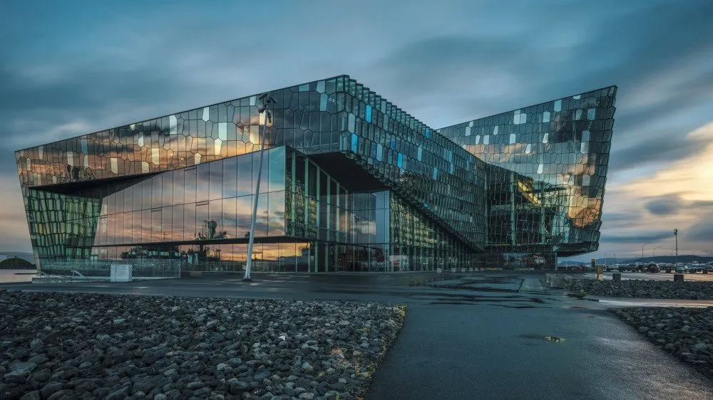 The modern glass façade of Harpa Concert Hall reflects a colorful Icelandic sunset, showcasing its architectural brilliance