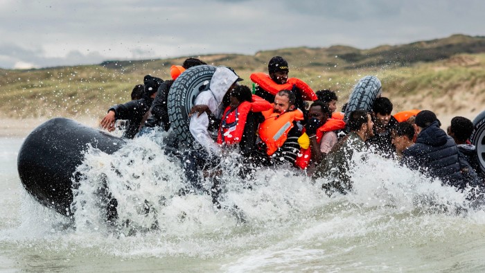 Migrants board a smuggler’s inflatable dinghy in an attempt to cross the English Channel