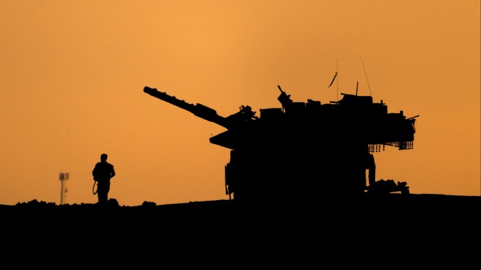 An Israeli military vehicle and soldier are seen in silhouette near the Gaza border