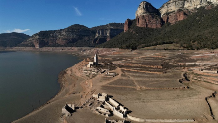 Residents walk on cracked ground next to the village of San Roman de Sau, at Sau reservoir in Spain