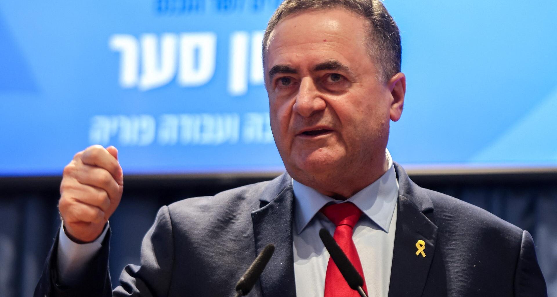 Der israelische Verteidigungsminister Katz spricht in Mikrofone und hebt dabei seine rechte Faust.