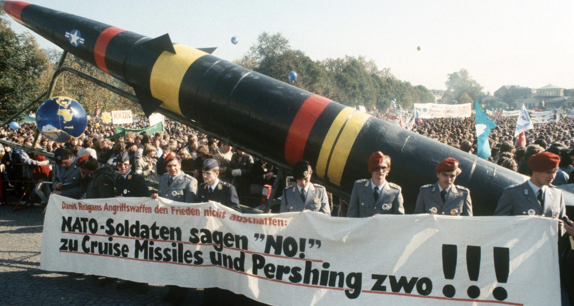 Soldaten der Bundeswehr in Uniform laufen mit einem Transparent und einer Pershing-II-Attrappe bei einer Demonstration gegen die NATO-Hochrüstung.