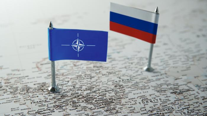 Landkarte, darauf die Fahnen der Nato  und von Russland
