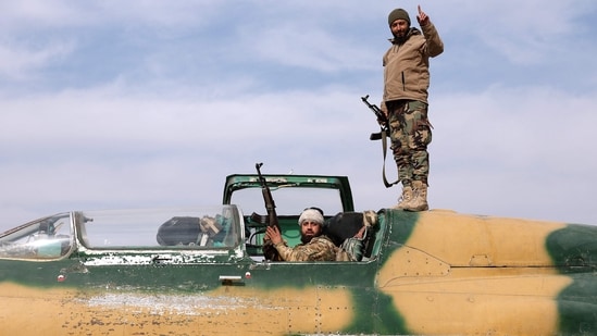 Opposition fighters gesture as they check a Syrian army jet after they took over a military airbase near the central city of Hama. Opposition fighters gesture as they check a Syrian army jet after they took over a military airbase near the central city of Hama.
