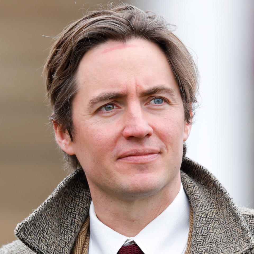A headshot of Edoardo Mapelli Mozzi wearing a tweed coat and white shirt looking off to the side.