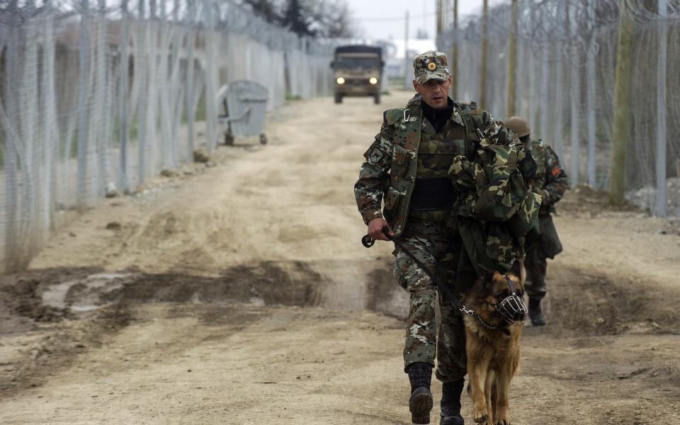 Macedonian soldiers patrol near the double razor wire at the Macedonian-Greek border