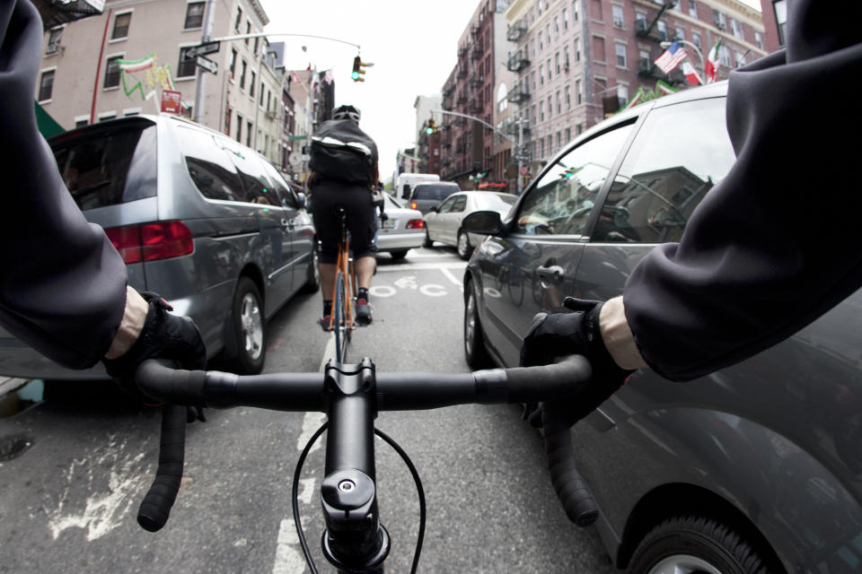 Cyclist's view of riding a bike through a busy urban street, navigating between vehicles and traffic