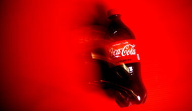 A bottle of Coca-Cola on a red background.
