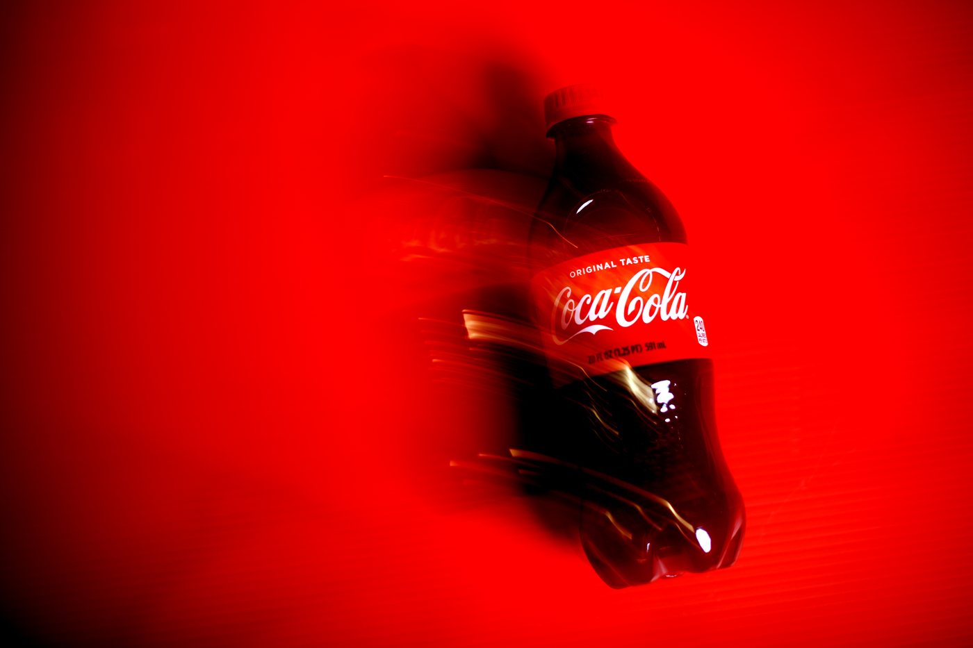 A bottle of Coca-Cola on a red background.