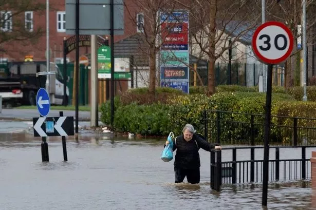 A resident wades through flooded waters in Wigan
